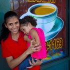 View "Young woman holds baby in front of coffee shop"